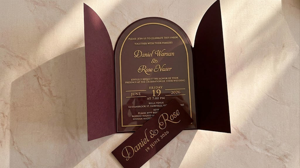 Front view of the open burgundy gatefold cover with the arched clear acrylic invitation inside and the matching printed paper band removed in front.