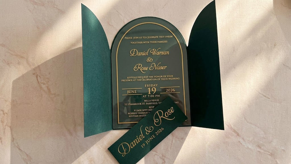 Front view of the open green gatefold cover with the arched clear acrylic invitation inside and the matching printed paper band removed in front.