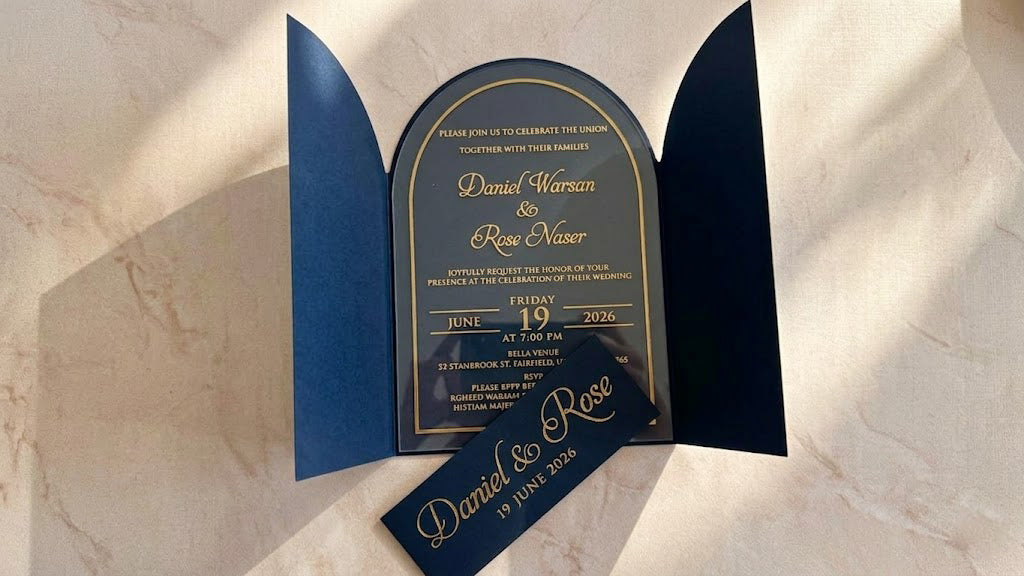 Front view of the open navy blue gatefold cover with the arched clear acrylic invitation inside and the matching printed paper band removed in front.