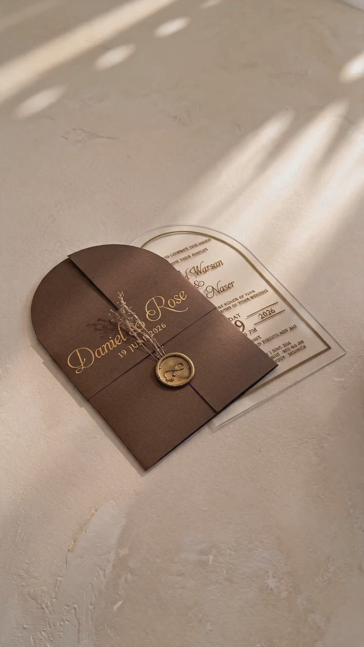 Video showing the brown cover's wax seal and dried flowers, then lifting and tilting the clear arched acrylic invitation to show its transparency.