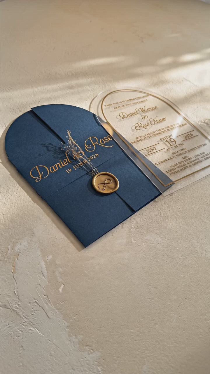 Video showing the navy blue cover's wax seal and dried flowers, then lifting and tilting the clear arched acrylic invitation to show its transparency.